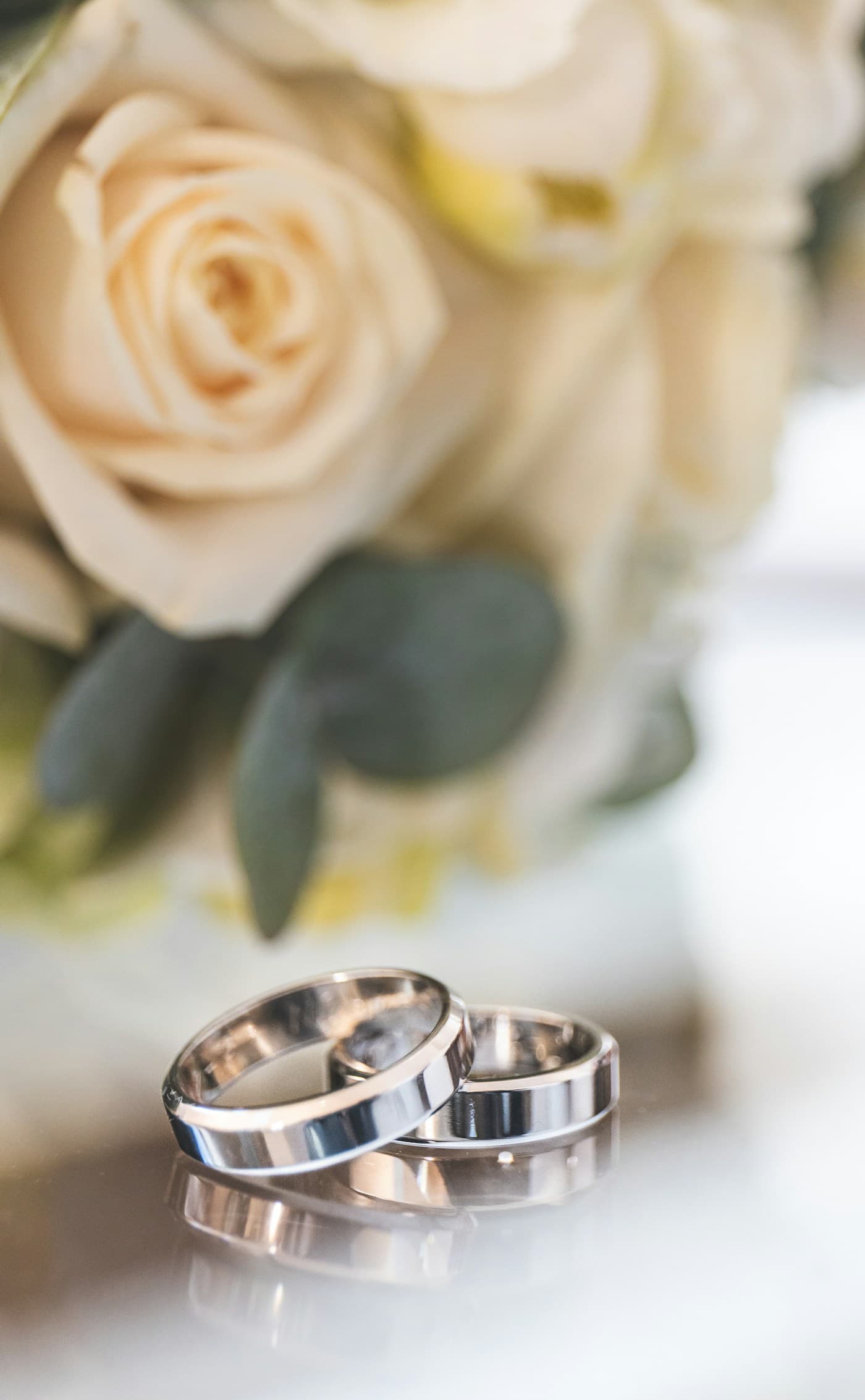 A pair of wedding bands in front of white roses